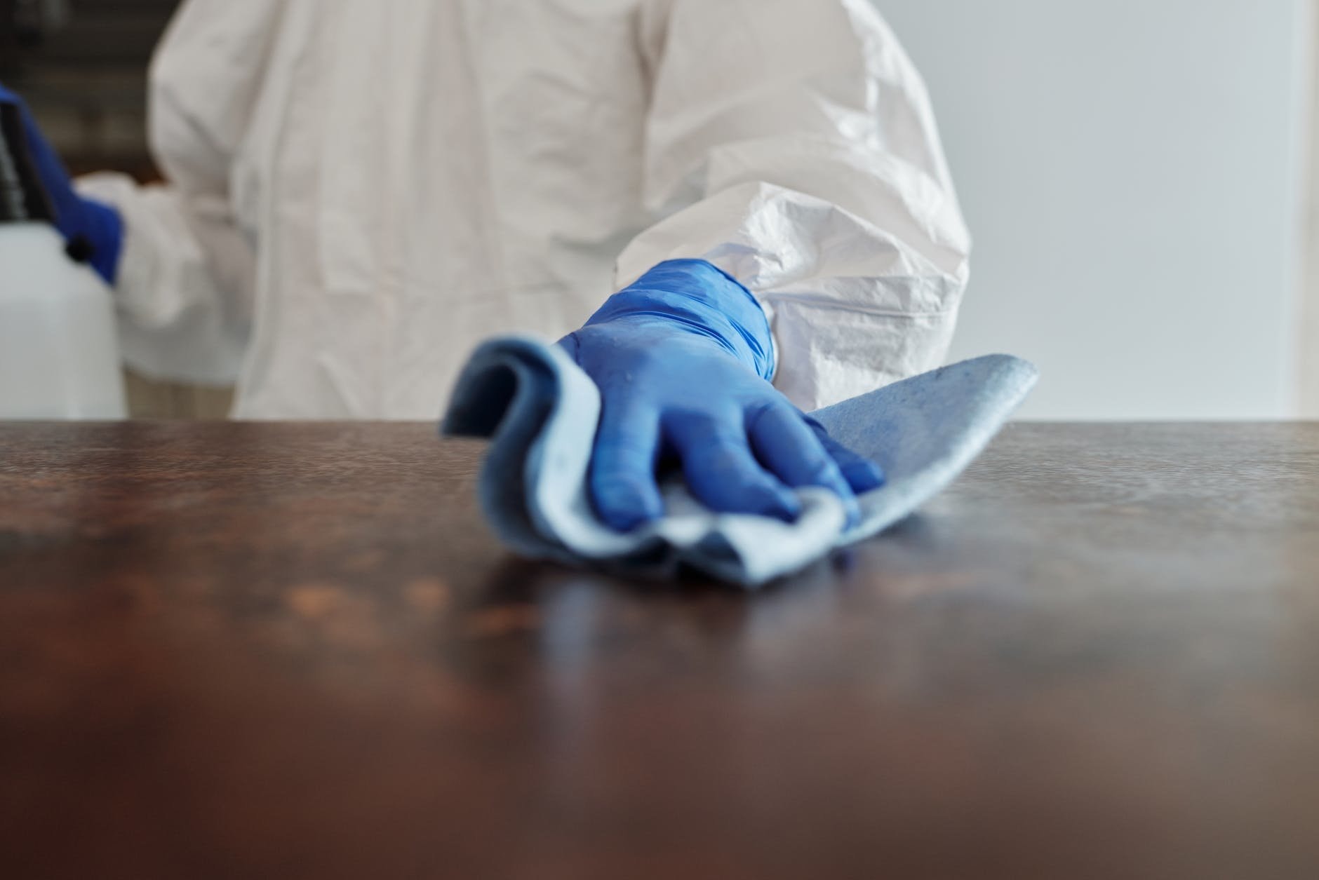 Cleaner wearing blue gloves wiping a tabletop